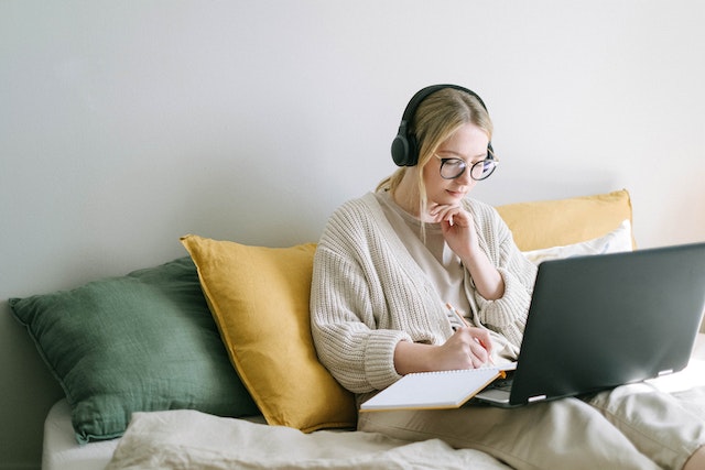 Mujer leyendo y mirando una computadora portátil